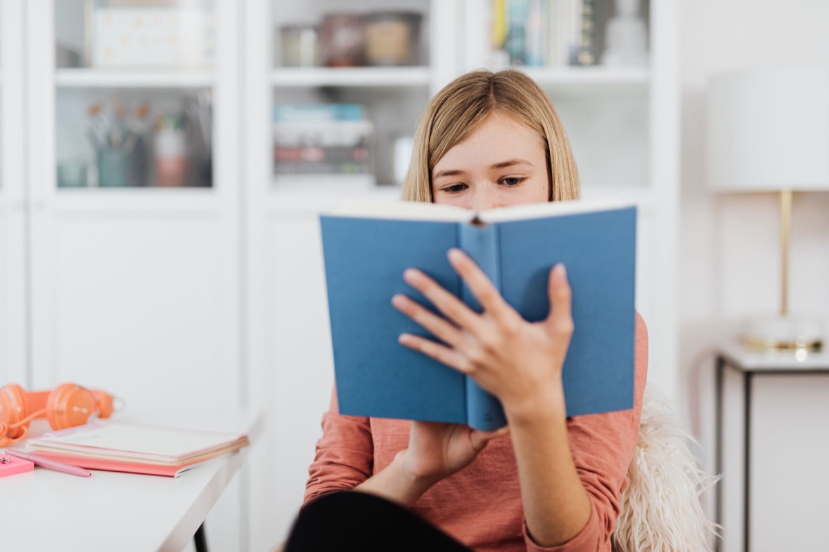 Une personne lisant un livre sous la lumière d'une lampe de bureau pour éviter la fatigue oculaire.