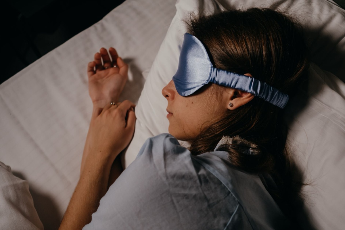 Masque de sommeil en soie posé sur un lit propre.