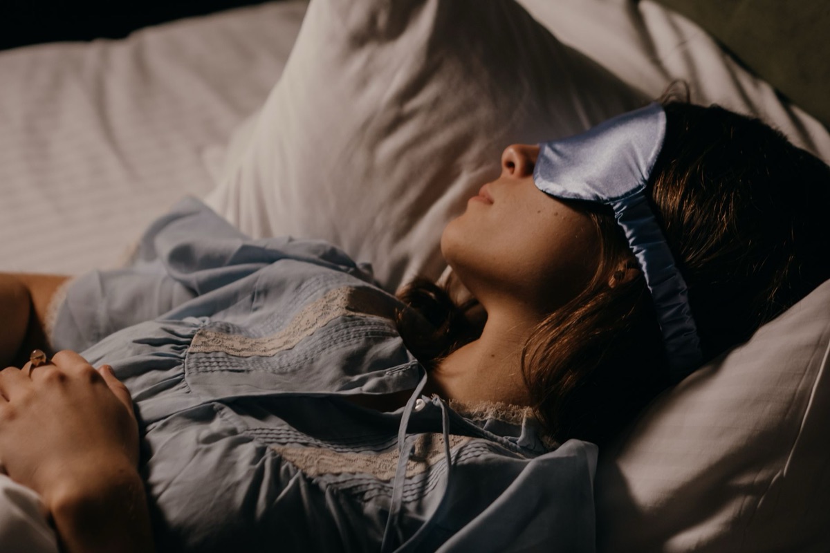 A person applying a warm eye compress to soothe tired eyes before sleep.