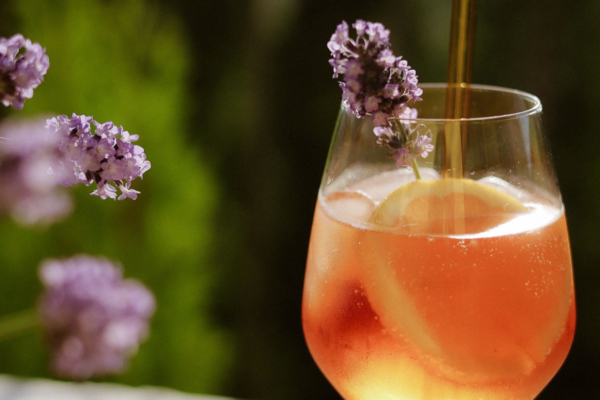 A glass of water and lavender sprigs on a wooden nightstand.