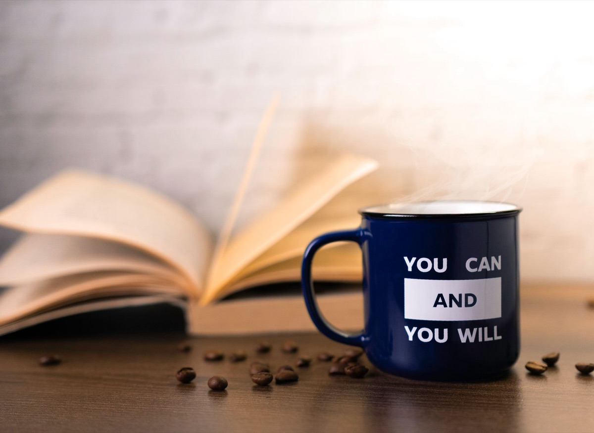 A closed book and a steaming ceramic mug on a cozy surface.