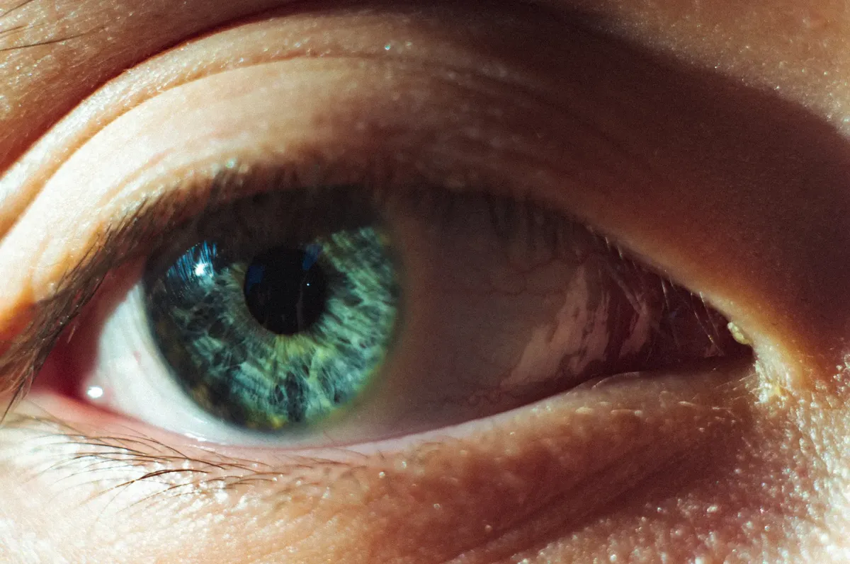 Extreme close-up photo of a human eye showing detailed green iris and pupil.